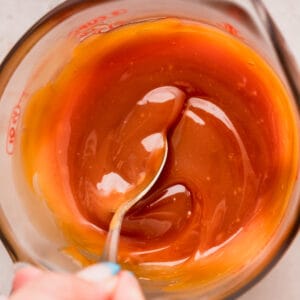 Mixing homemade salted caramel in a glass container.