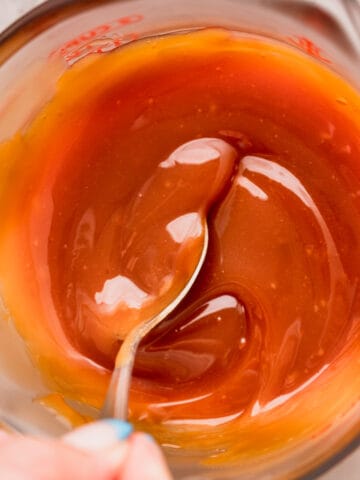 Mixing homemade salted caramel in a glass container.