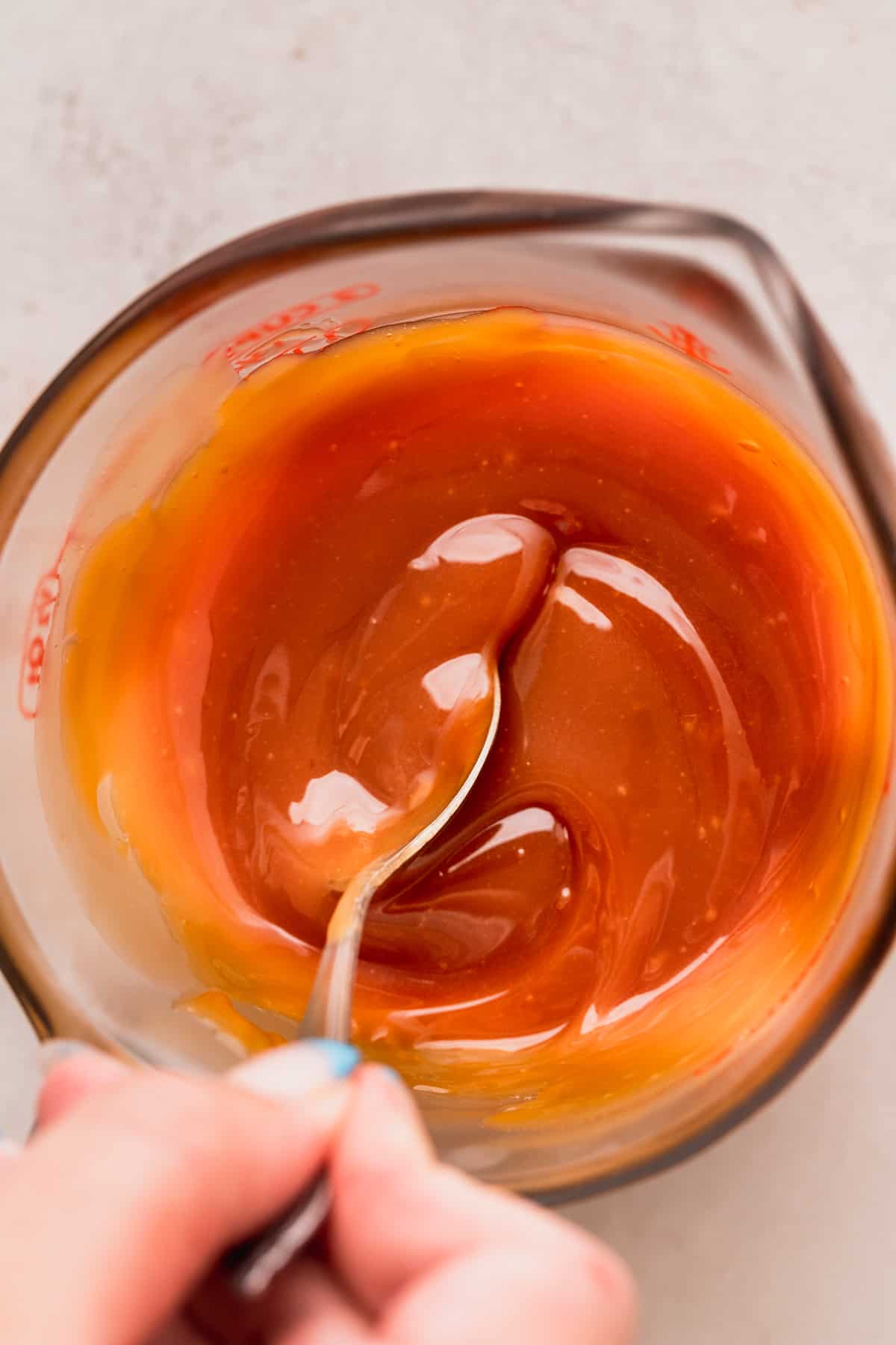 Mixing homemade salted caramel in a glass container.