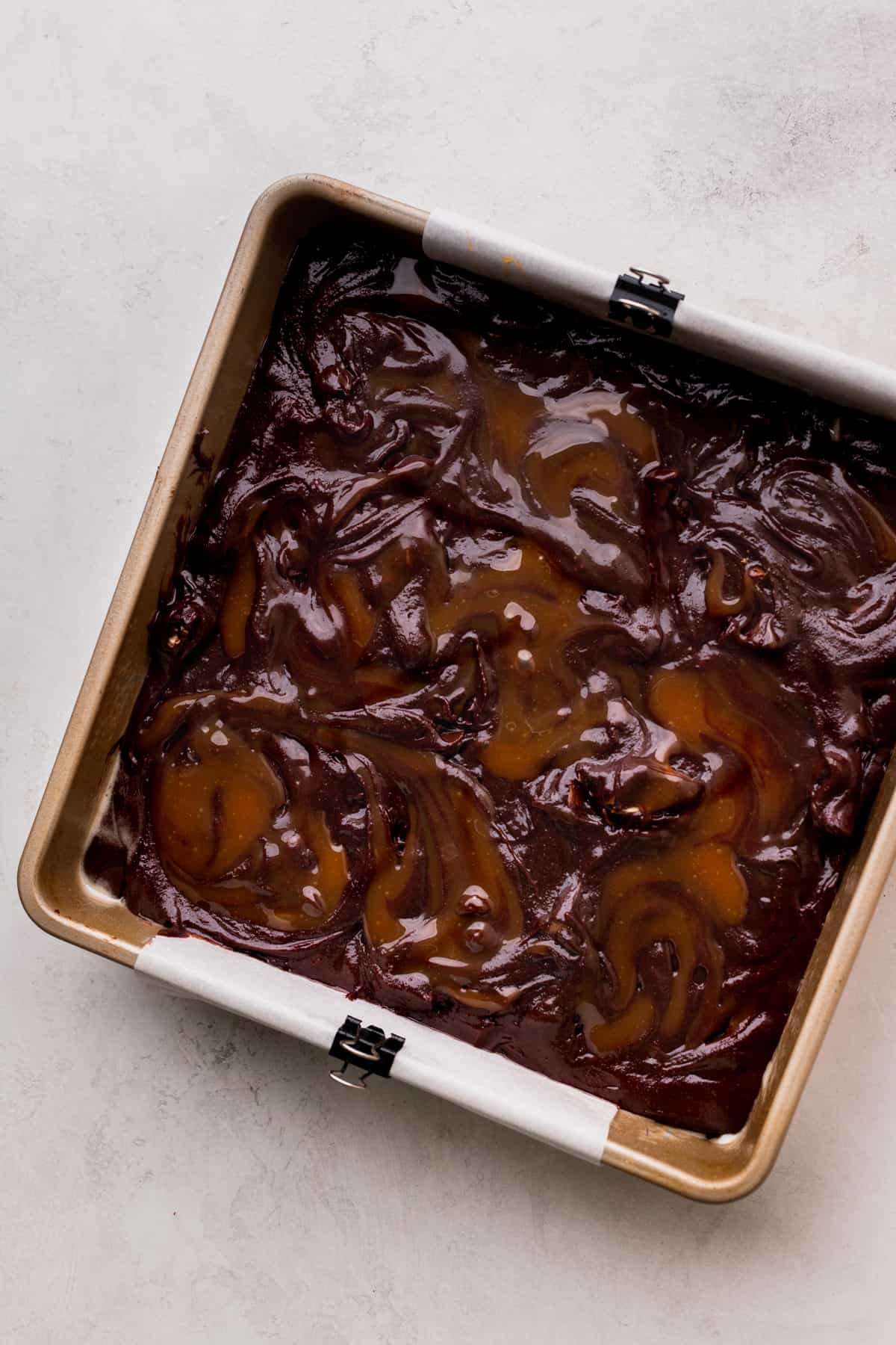 Caramel on top of brownie batter in a pan.