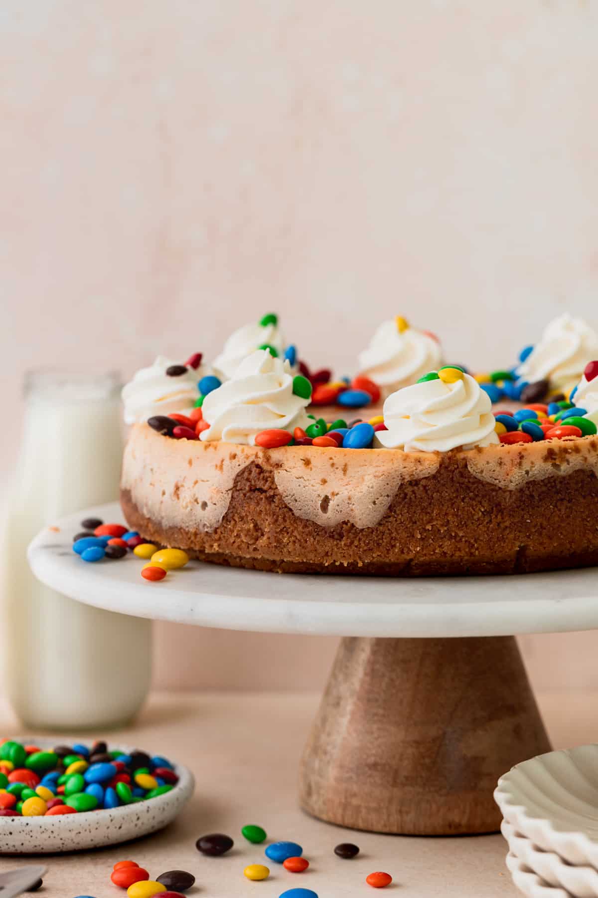 m&m cheesecake on a cake stand.