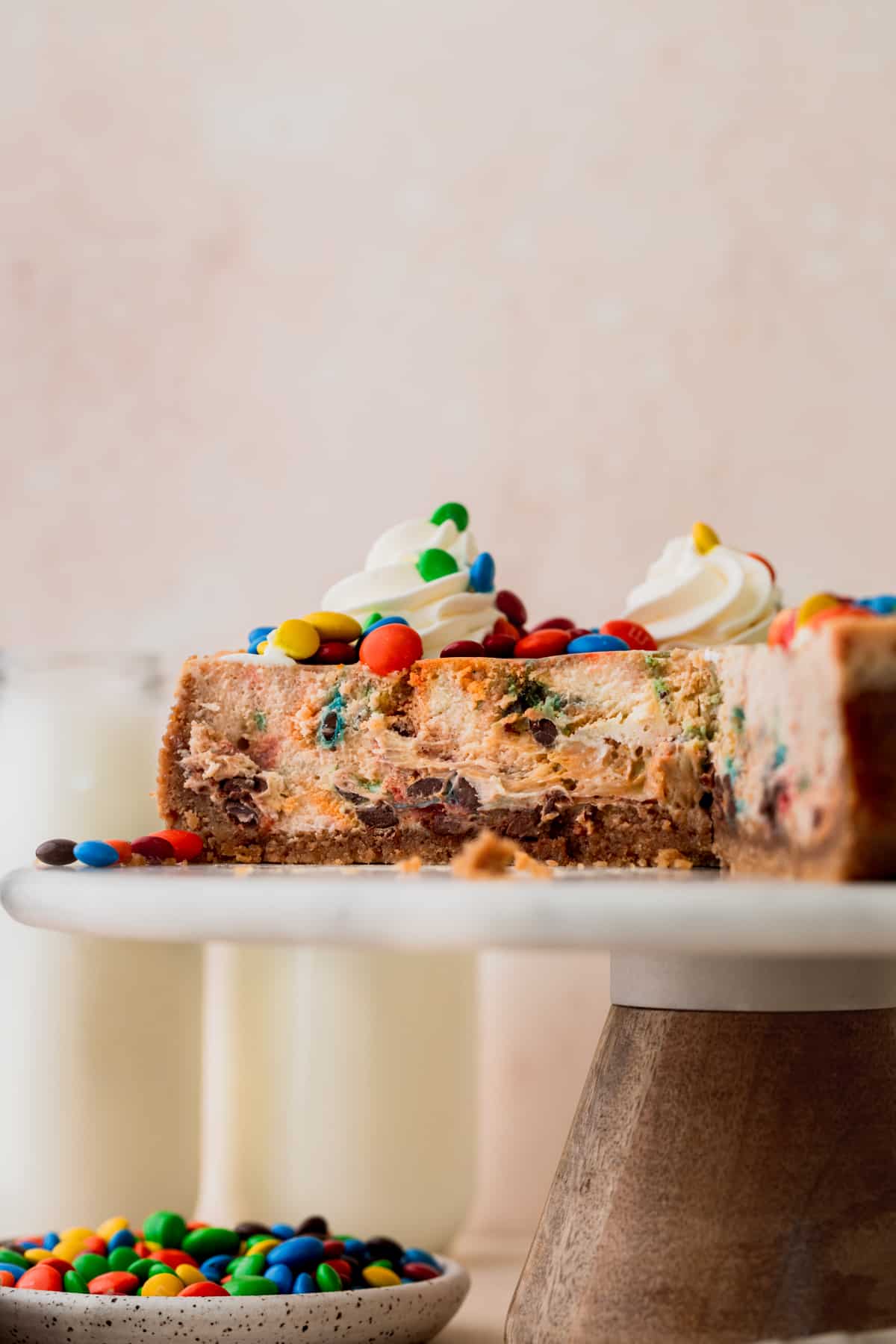 M&M cheesecake on a cake stand cut into.