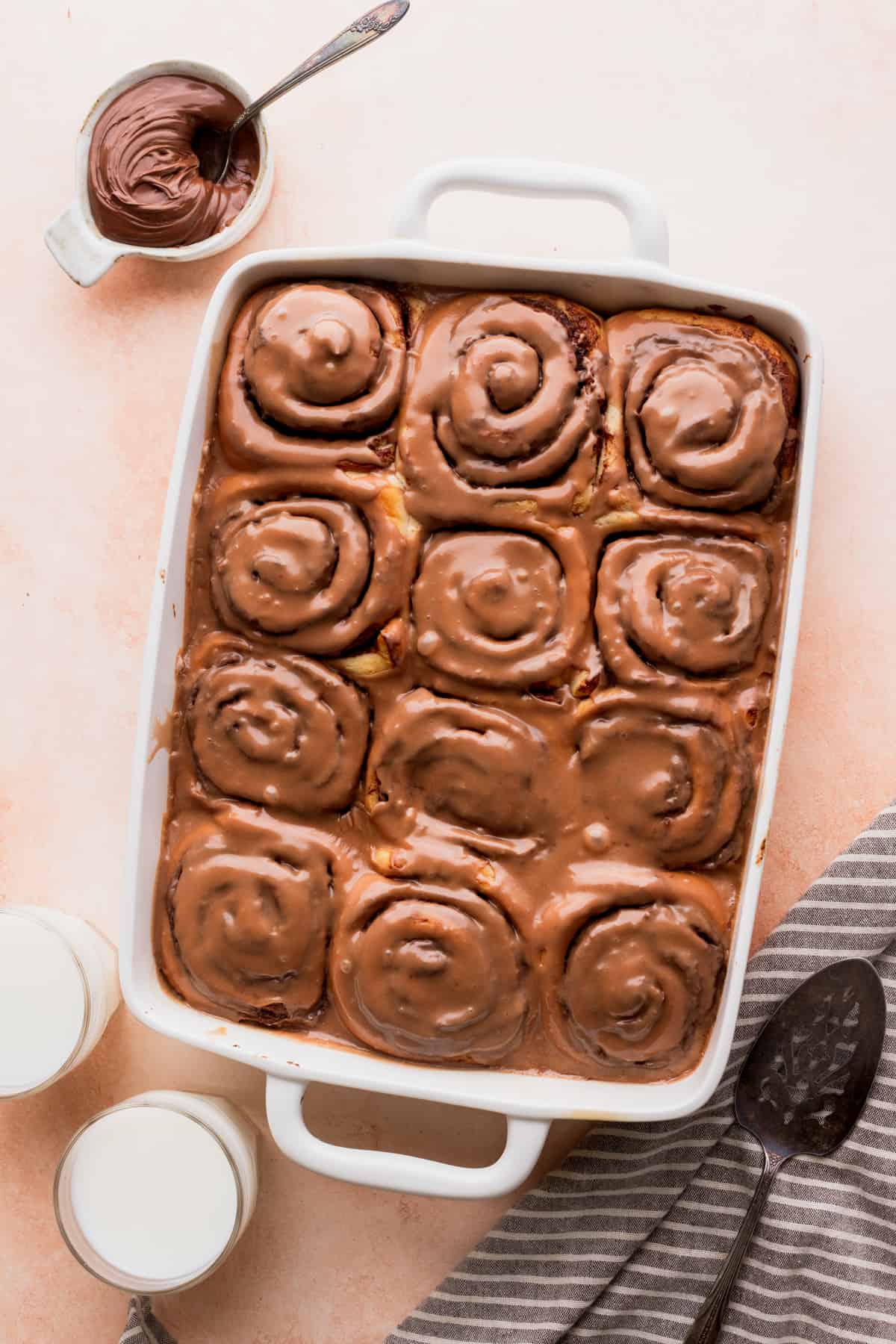 Iced rolls in a baking with a bowl of Nutella.