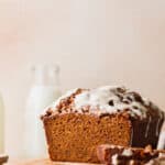 Pumpkin bread with cream cheese frosting on a wood board.