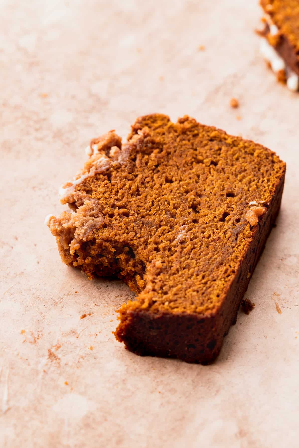 A bite missing from pumpkin bread with cream cheese frosting.