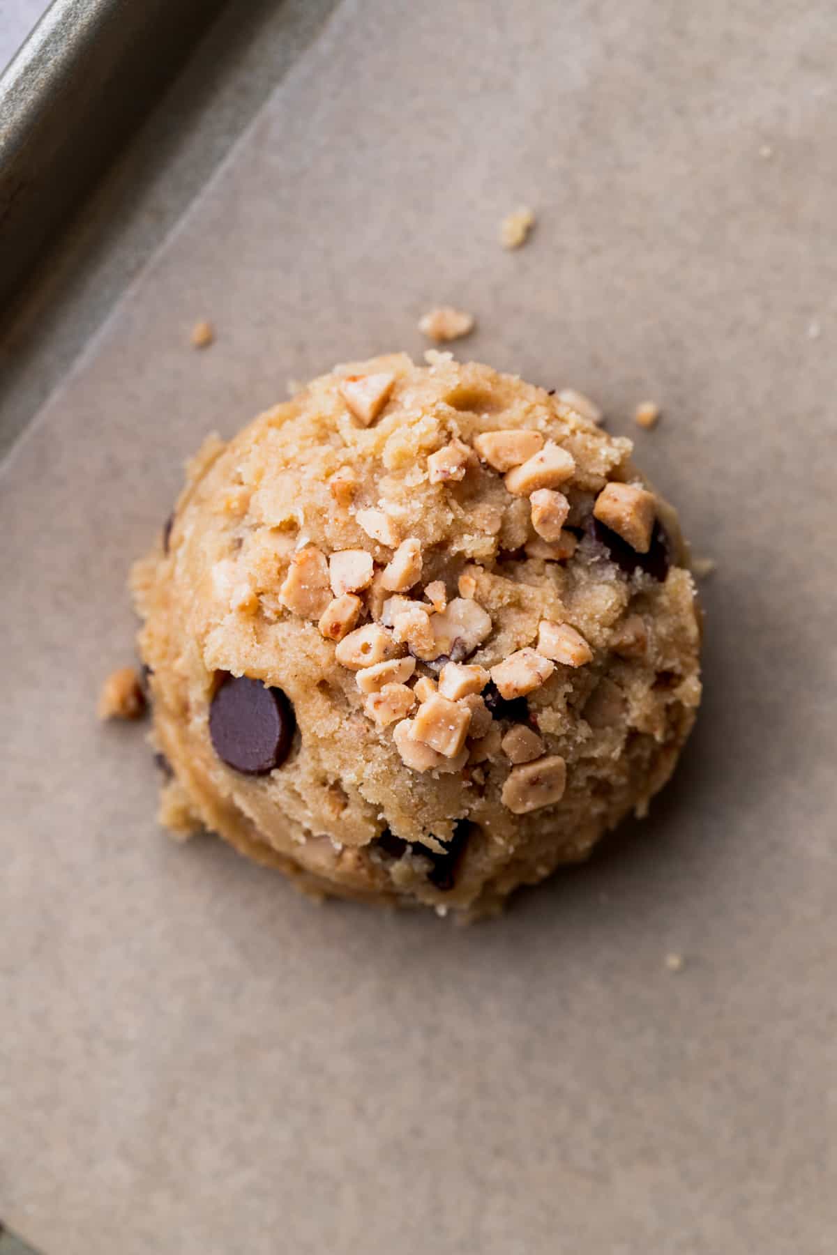 Cookie dough ball on top of parchment paper.