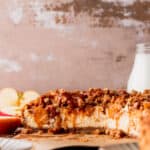 Apple crumble cheesecake cut in half on a board.