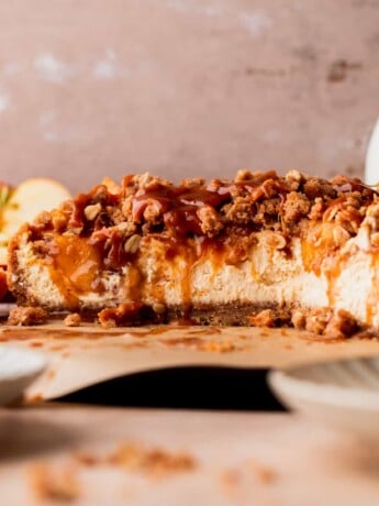 Apple crumble cheesecake cut in half on a board.
