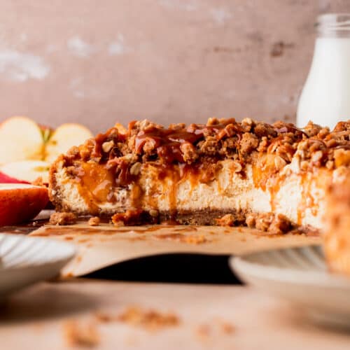 Apple crumble cheesecake cut in half on a board.