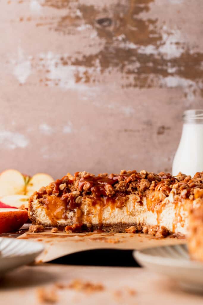 Apple crumble cheesecake cut in half on a board.