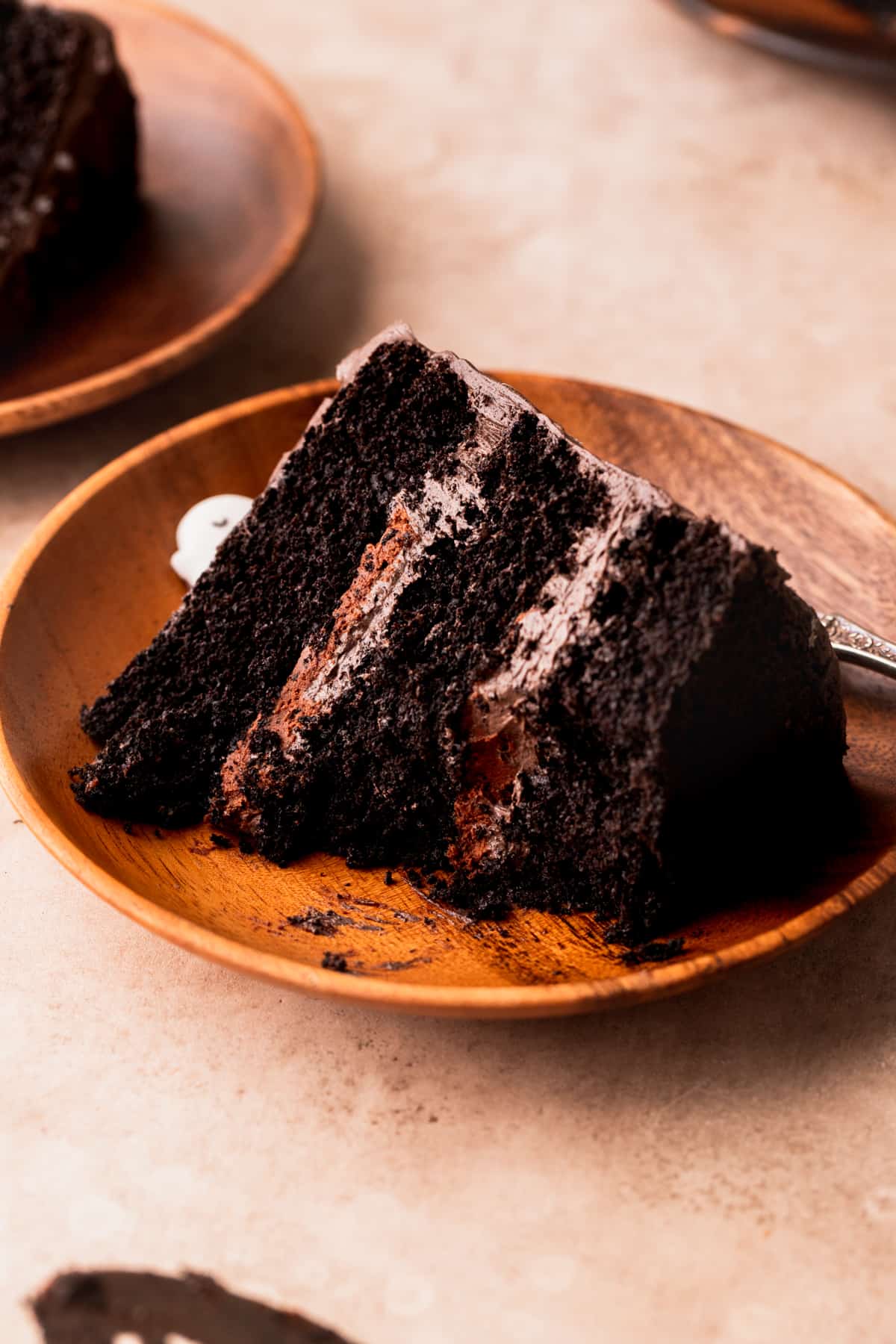 One slice on cake on a wood plate with a bite missing.