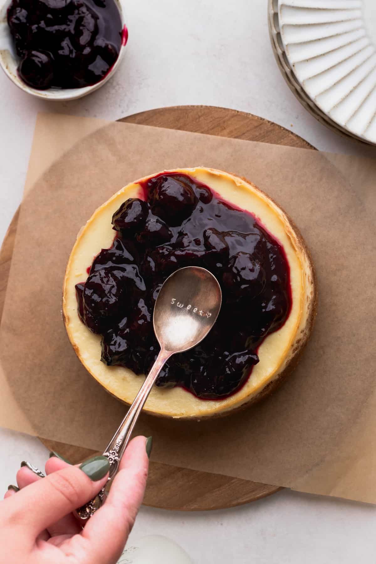 Spreading cherry topping on top of cheesecake.