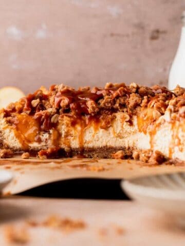 Apple crumble cheesecake cut in half on a board.