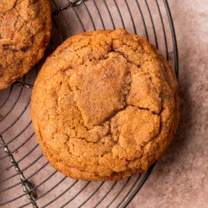 One chewy pumpkin snickerdoodle cookies on a wire rack.