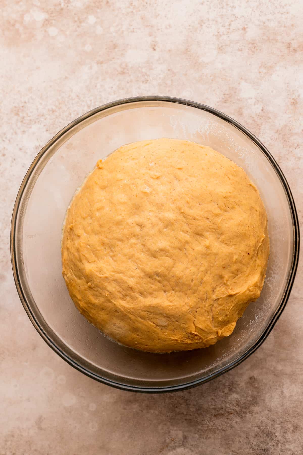 Risen dough in a glass bowl.