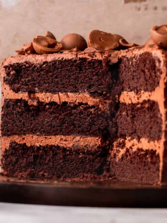 Chocolate truffle cake split in half on a wood board.