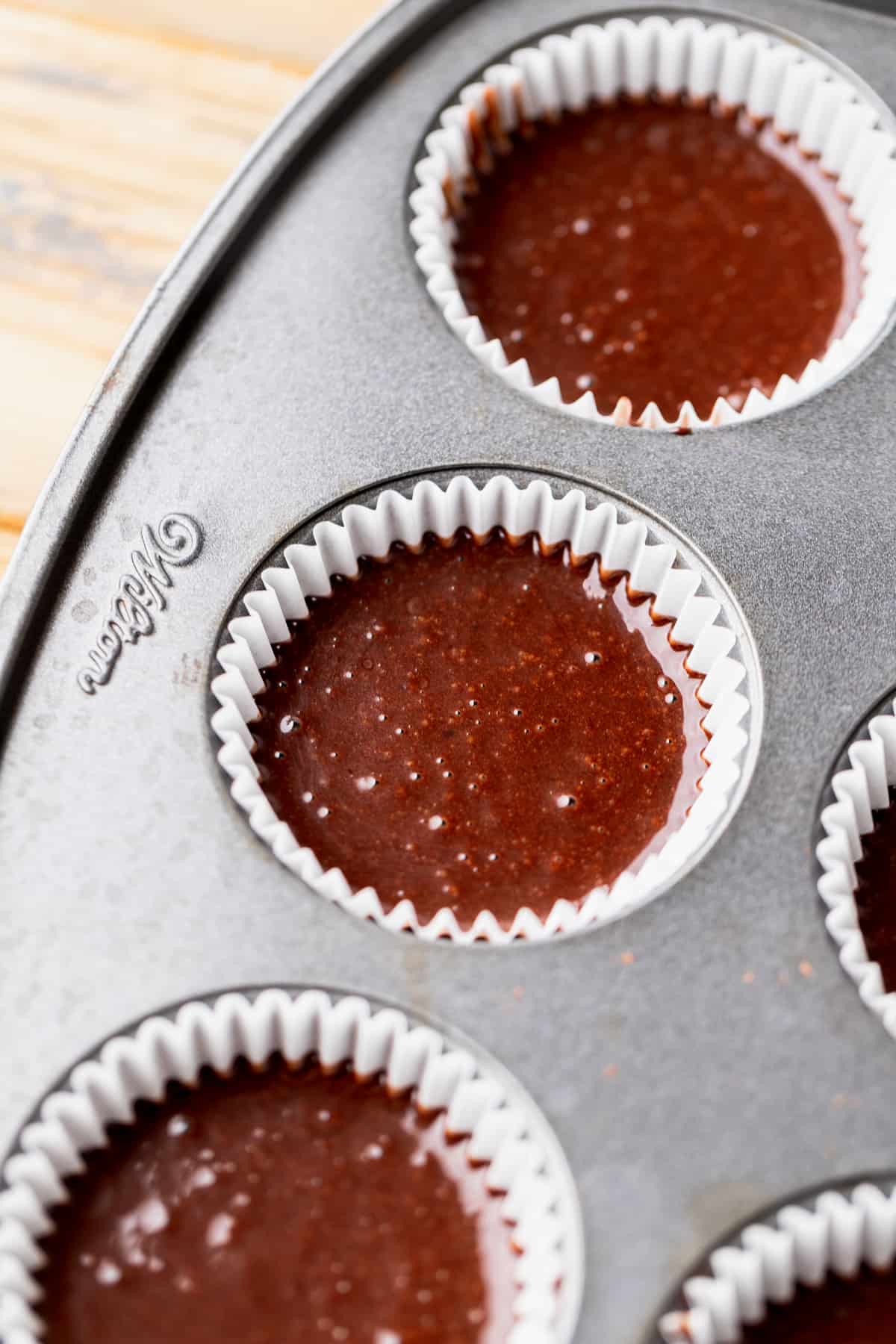 Chocolate cake batter in a cupcake pan.