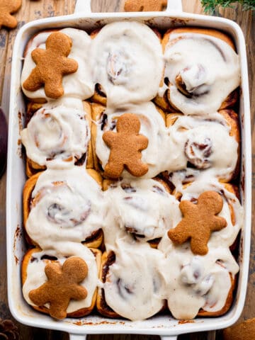 Gingerbread cinnamon rolls in a pan with a few gingerbread men on top.