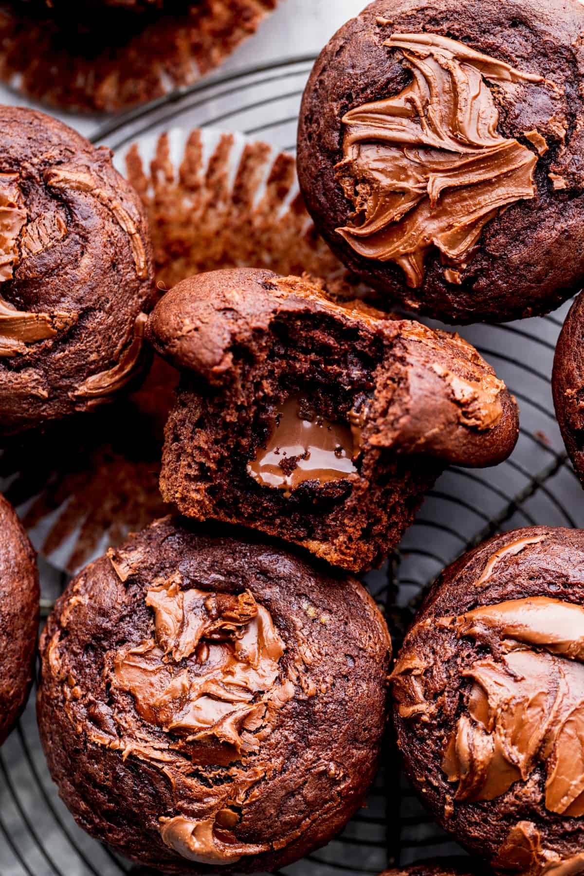 Nutella muffins with a bite missing on a wire rack.
