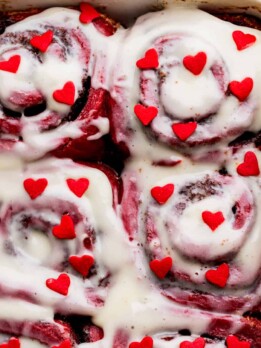 Red hearts on top of red velvet cinnamon rolls.
