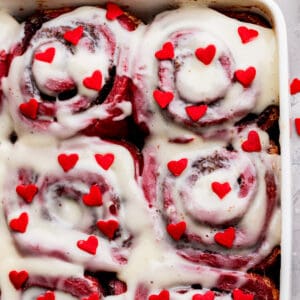 Red hearts on top of red velvet cinnamon rolls.