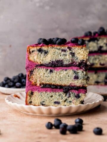 One slice of blueberry cake standing up on a plate.