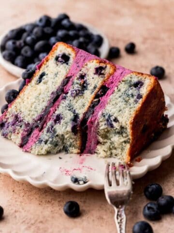 Bite missing from a piece of blueberry cake on a plate.