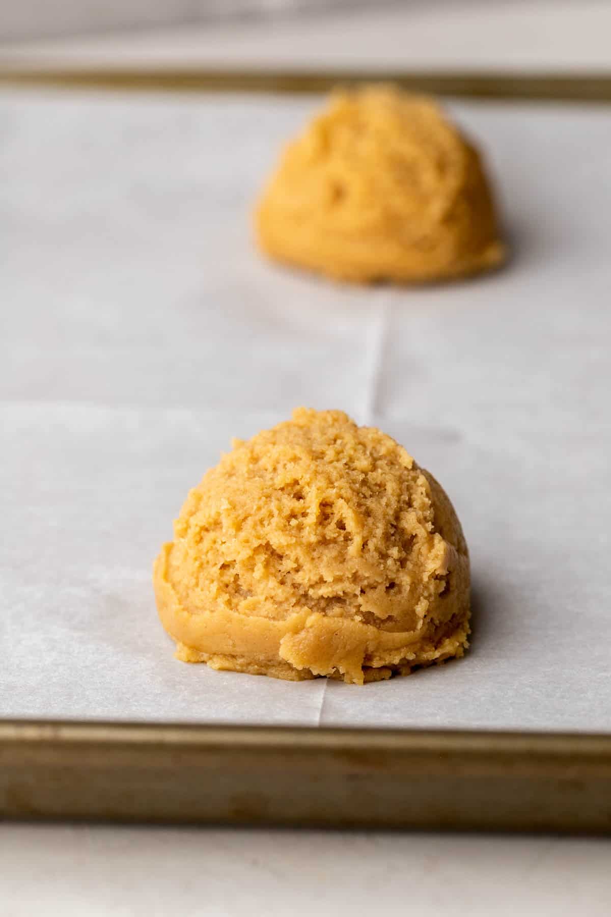 Peanut butter cookie dough ball on a cookie sheet.