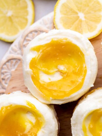 Decorated lemon bar cupcakes on a wood board.