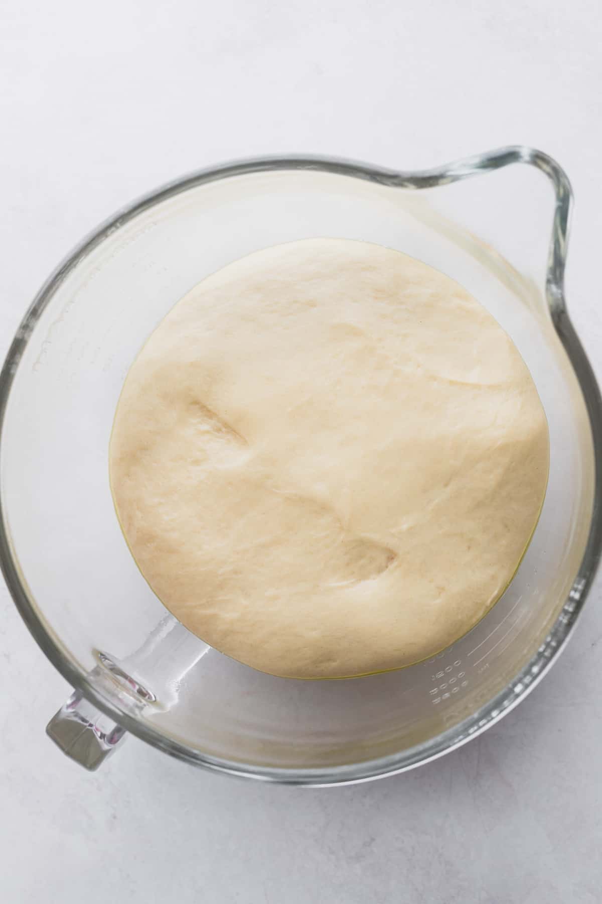 Dough after rising in a glass bowl.