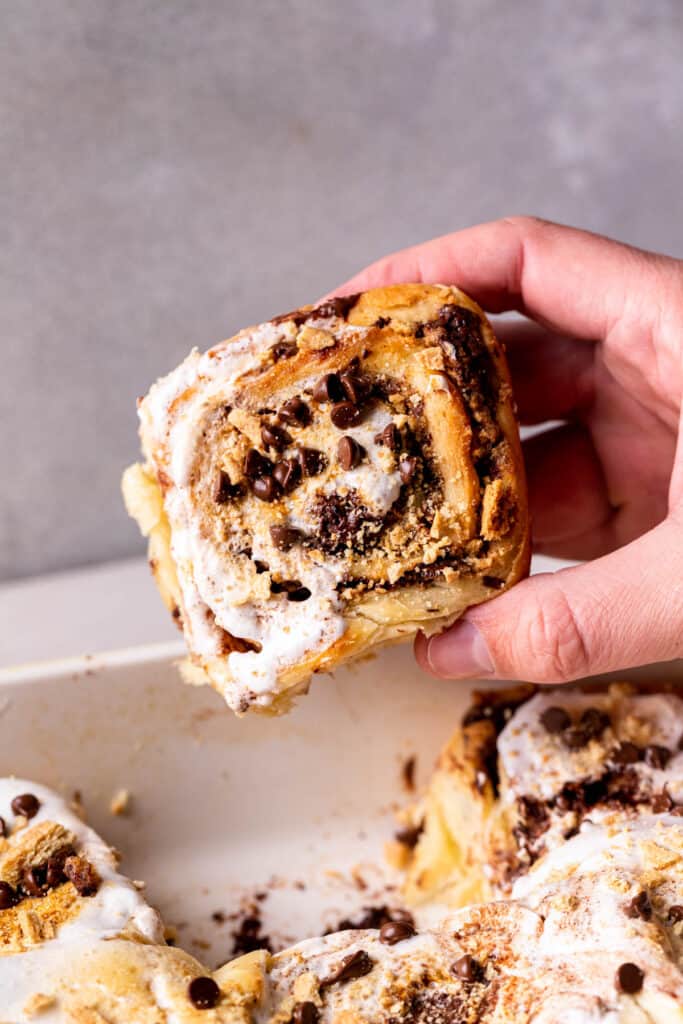 Taking one cinnamon roll out of the pan.