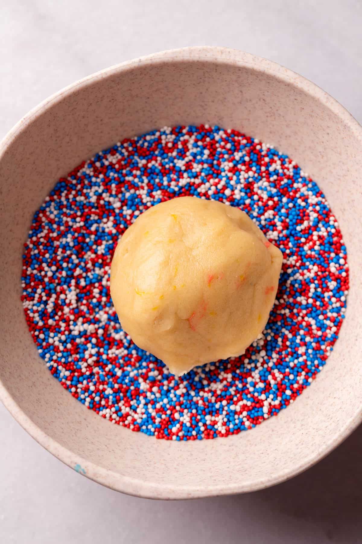 Cookie dough ball on top of sprinkles.