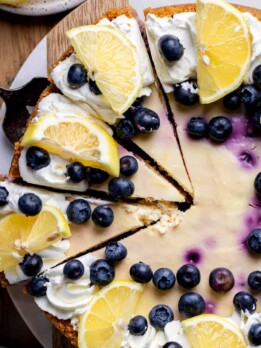 Decorated lemon blueberry cheesecake on a board.