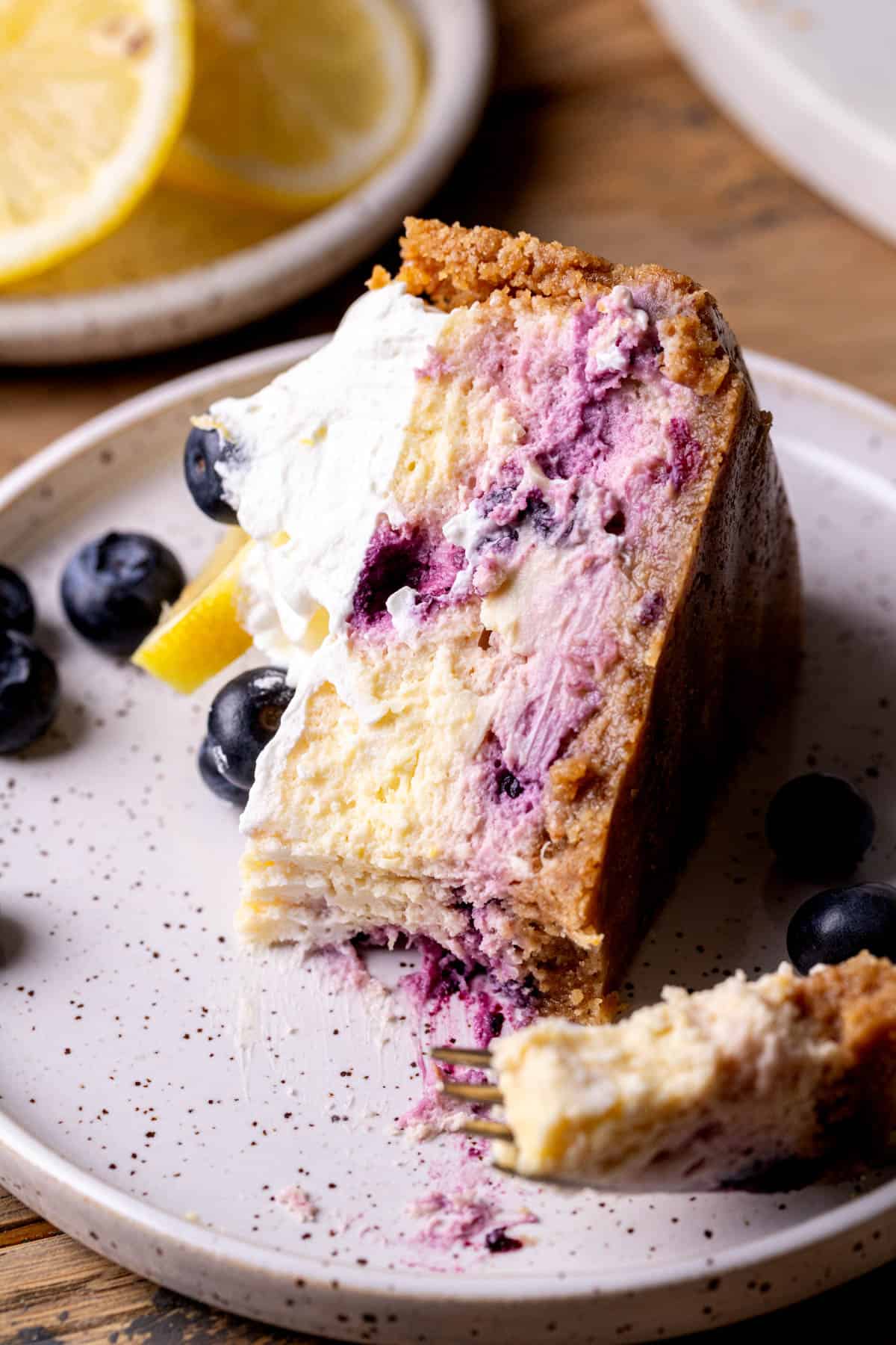 Bite missing from lemon blueberry cheesecake on a plate.
