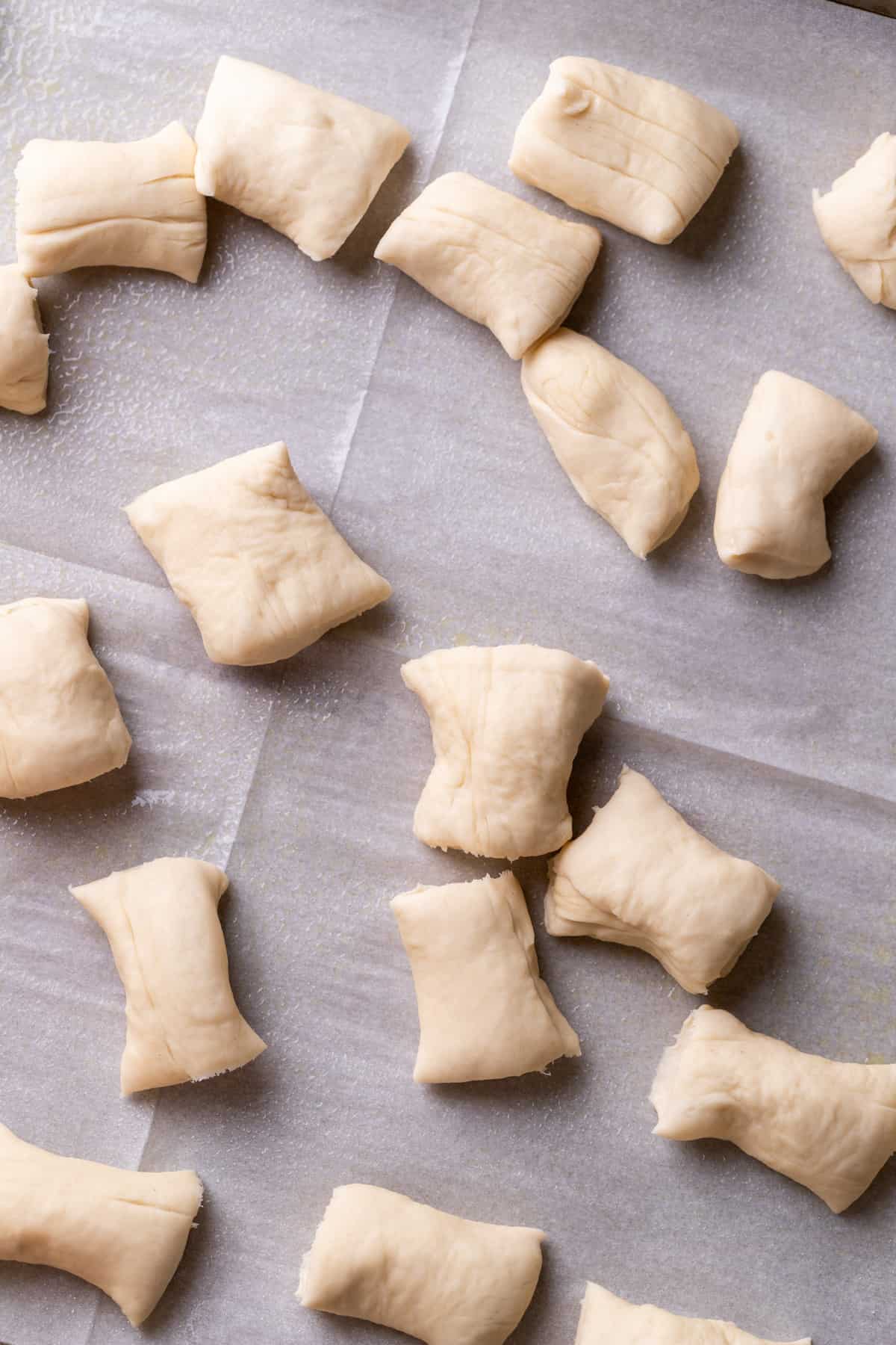 Raw pieces of dough on parchment paper.