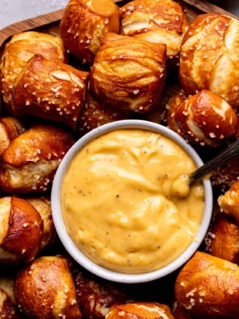 Soft pretzel bites on a board with cheese sauce.