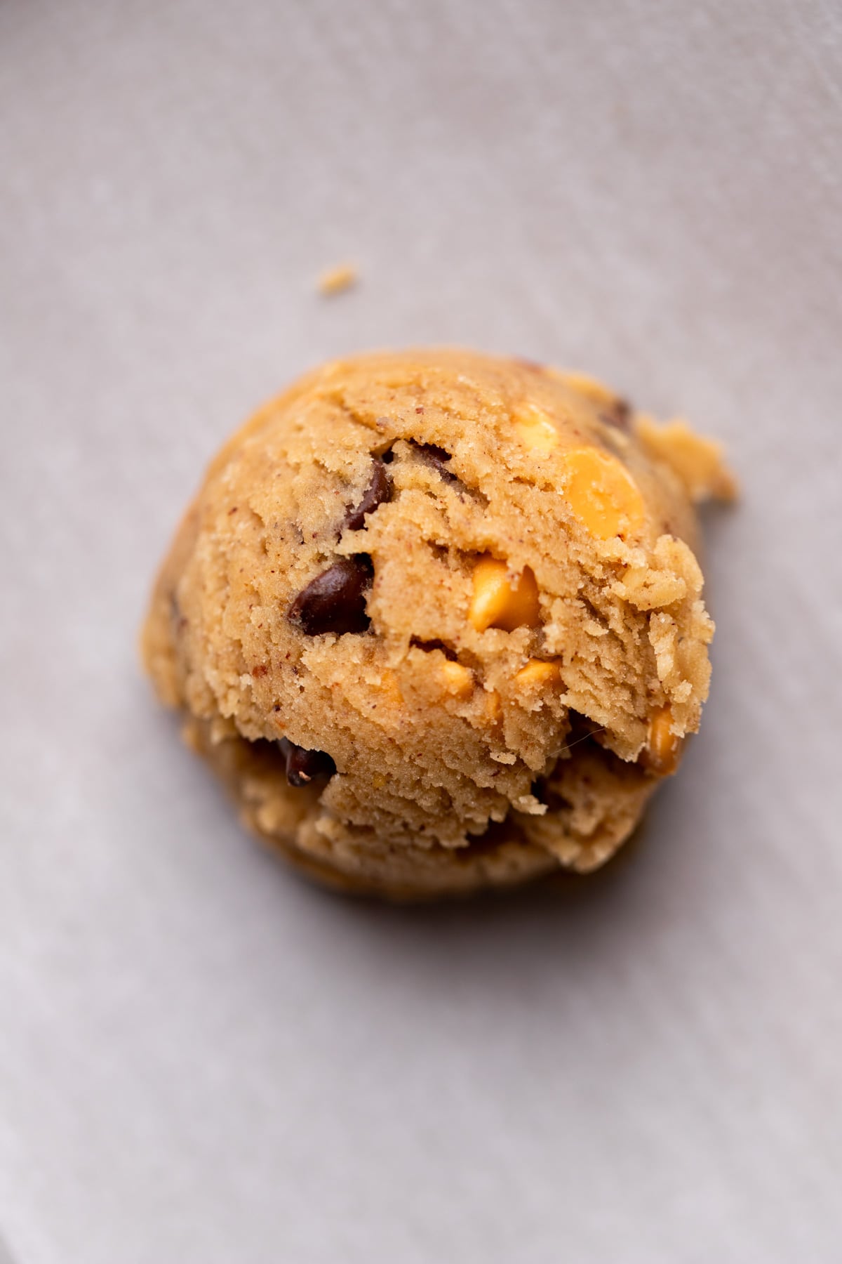 Cookie dough ball on parchment paper.