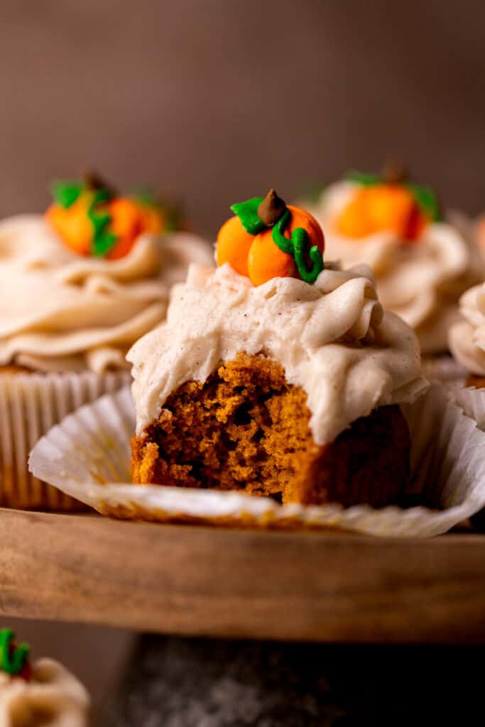 Bite missing from a pumpkin cupcake.