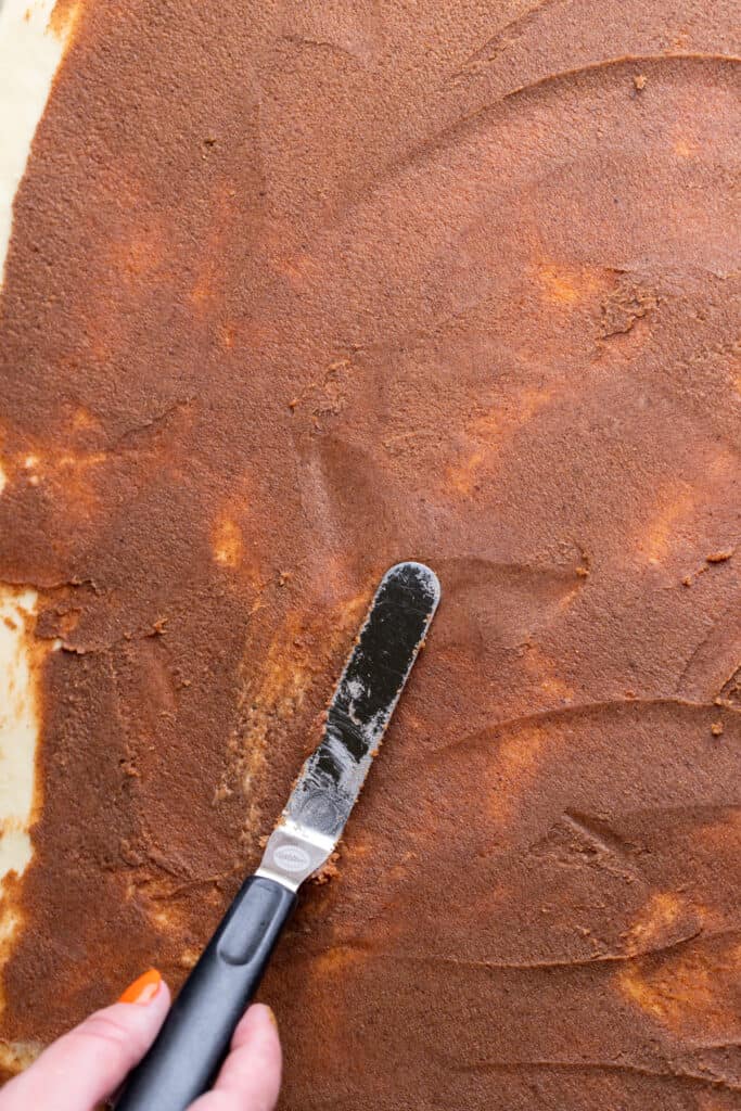 Spreading cinnamon filling over the dough.