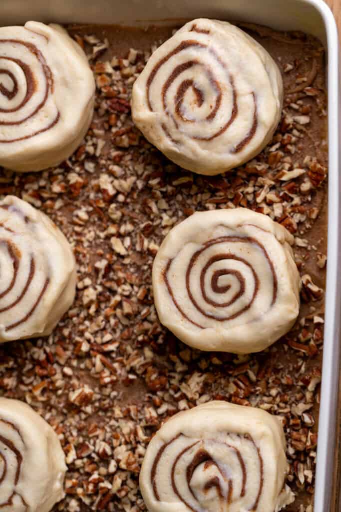 Raw cinnamon rolls on top of the sticky topping.