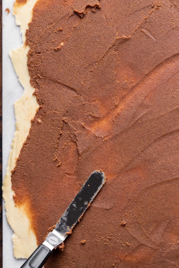 Spreading the cinnamon filling on top of the dough.