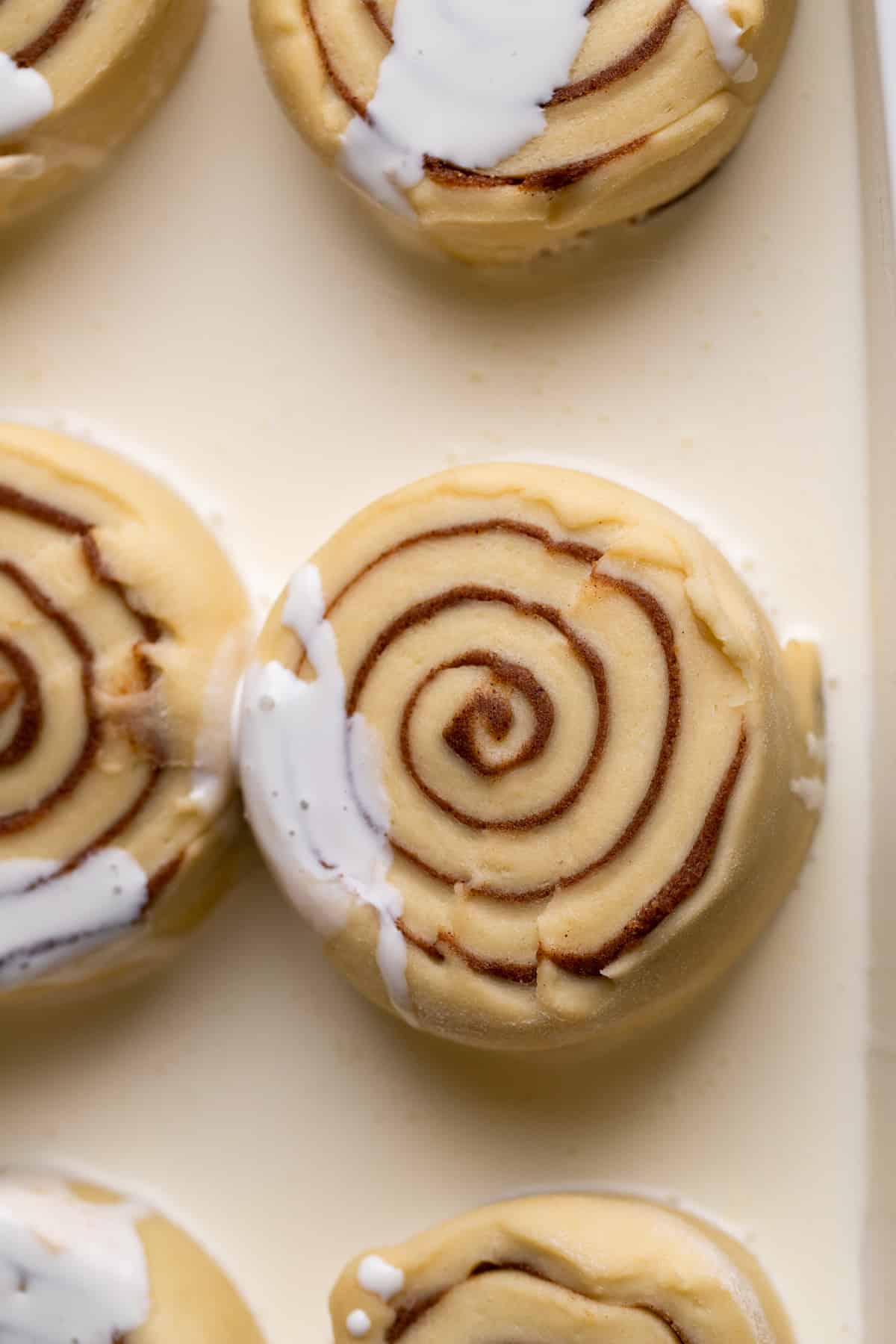 Raw cinnamon rolls with heavy cream in pan.