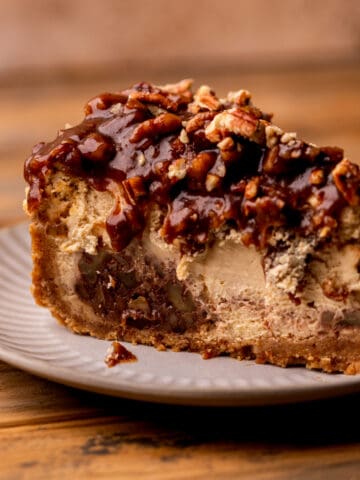 Pecan pie cheesecake slice on a plate.