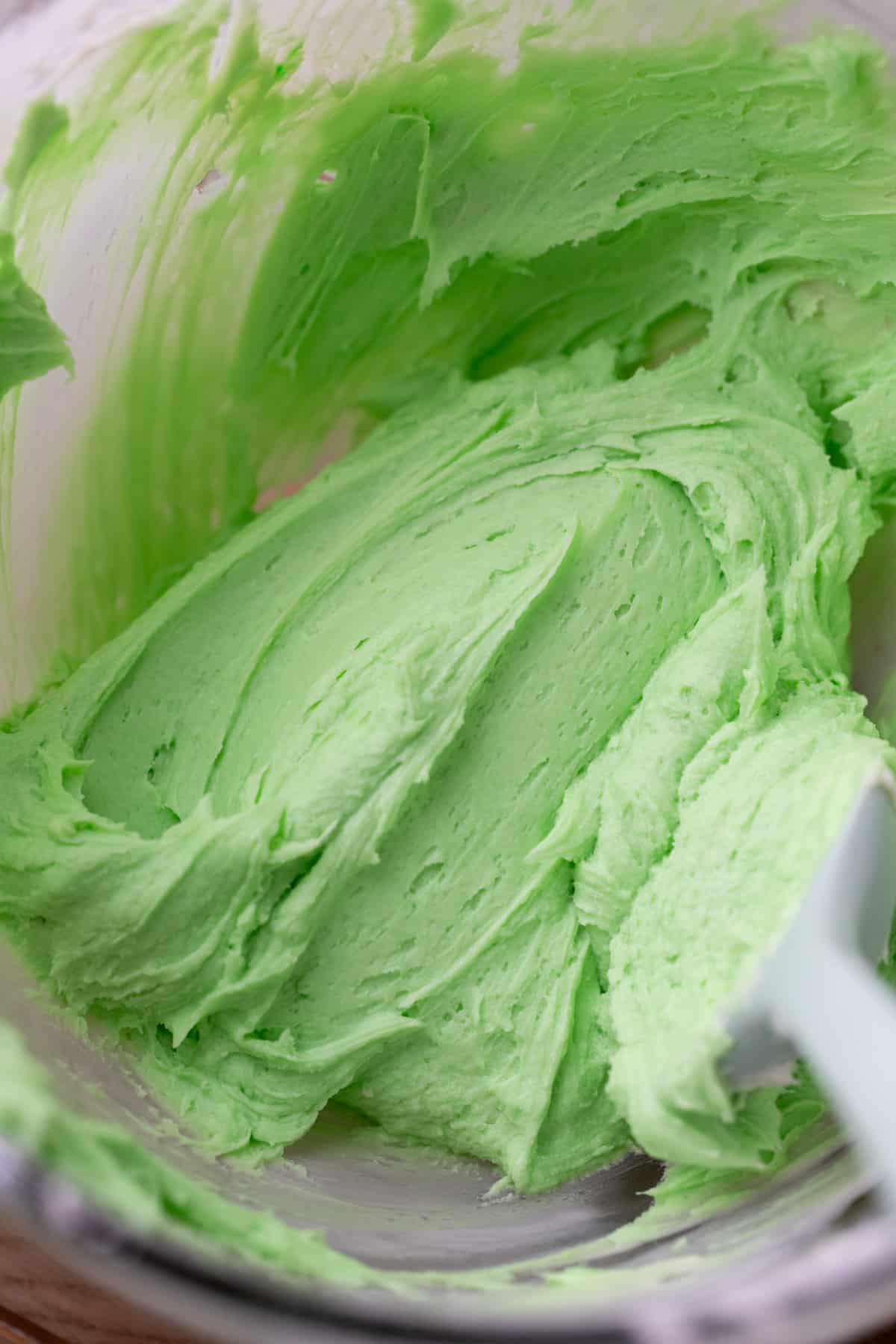 Green cream cheese frosting in a glass bowl.