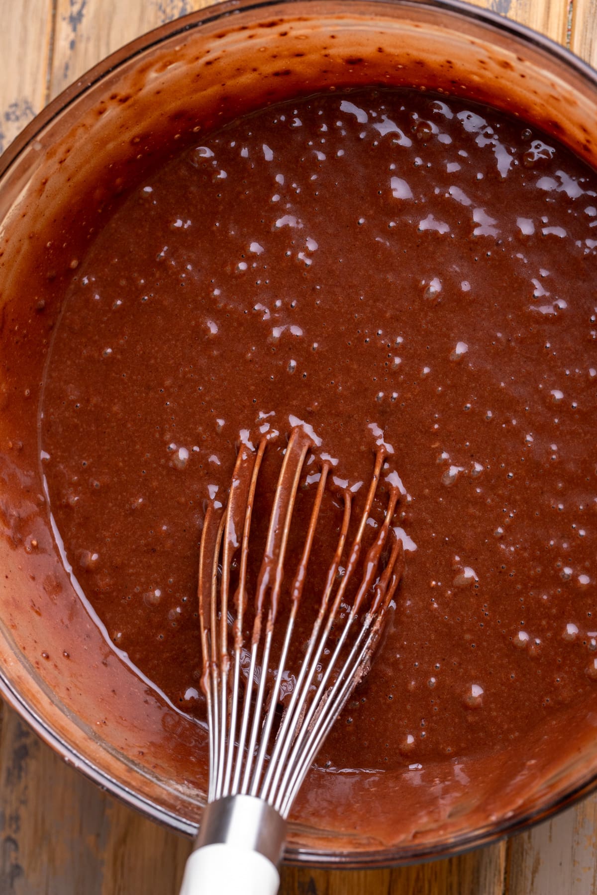 Chocolate cake batter in a glass bowl.