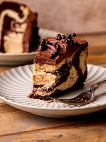 Bite missing from standing up piece of cheesecake on a plate.