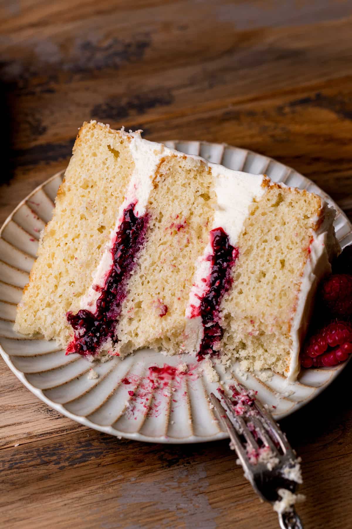 Bite missing from white chocolate raspberry cake on a plate.
