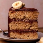 One slice of banana cake with chocolate frosting on a plate.