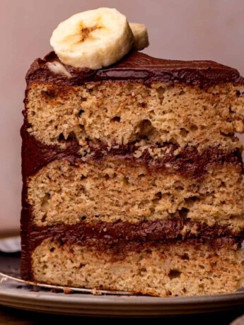 One slice of banana cake with chocolate frosting on a plate.