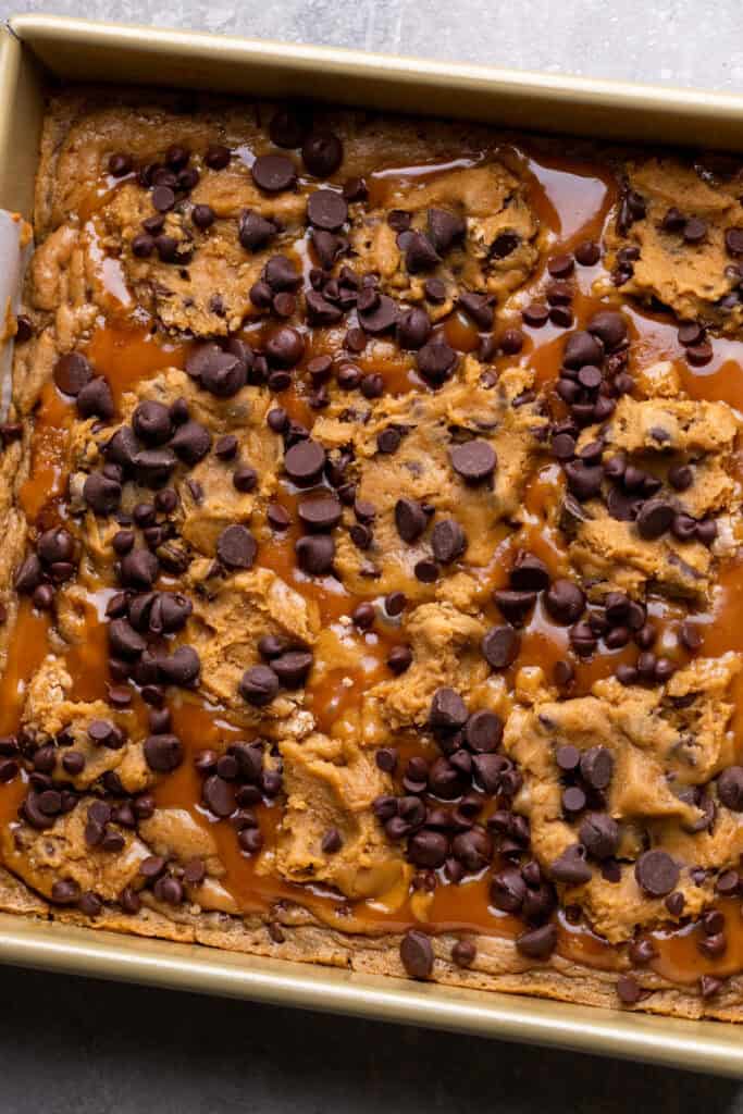 Cookie dough on top of caramel in the pan.